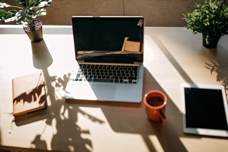Laptop, notitieboek, koffie en tablet.